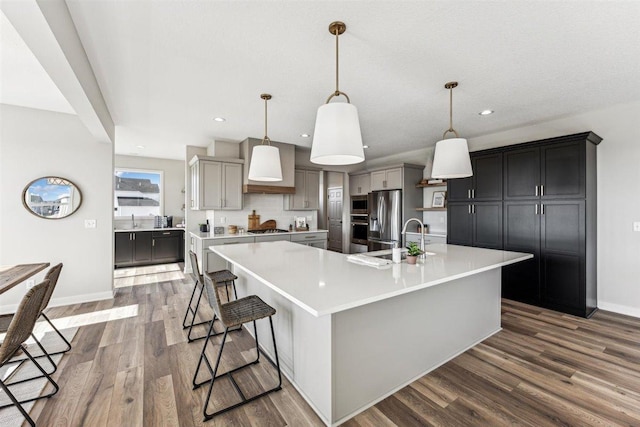 kitchen featuring gray cabinetry, backsplash, pendant lighting, a spacious island, and appliances with stainless steel finishes