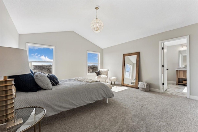 carpeted bedroom with a chandelier, ensuite bath, and lofted ceiling