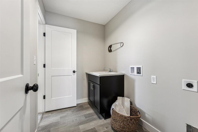 laundry area with electric dryer hookup, cabinets, sink, light hardwood / wood-style flooring, and washer hookup