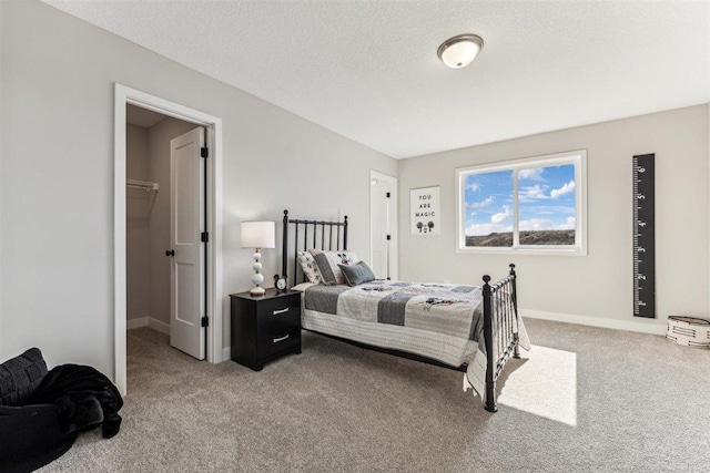 carpeted bedroom with a walk in closet, a closet, and a textured ceiling