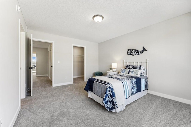 carpeted bedroom with a spacious closet, a textured ceiling, and a closet