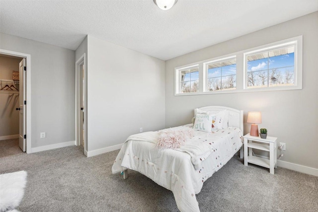 bedroom with a spacious closet, a closet, carpet, and a textured ceiling