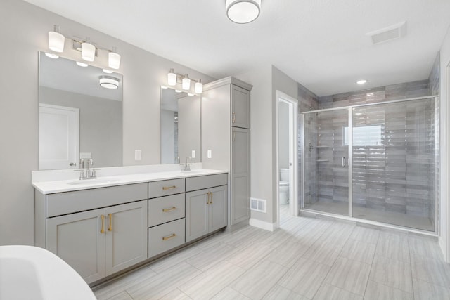 15701 Aquila Ave, Savage, MN 55378 - bathroom featuring a sink, double vanity, toilet, a shower stall, and visible vents