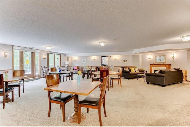 carpeted dining room featuring a textured ceiling and a tiled fireplace