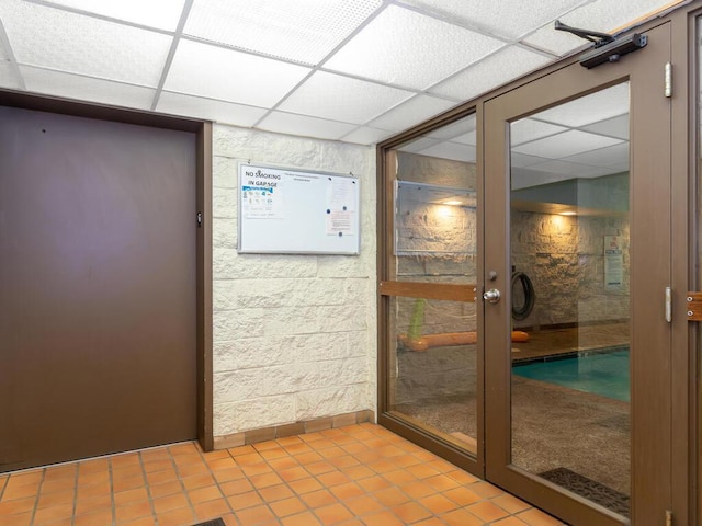 doorway featuring light tile patterned flooring and a drop ceiling