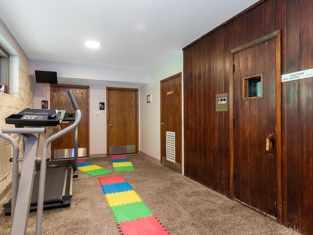 exercise area with carpet floors and wood walls