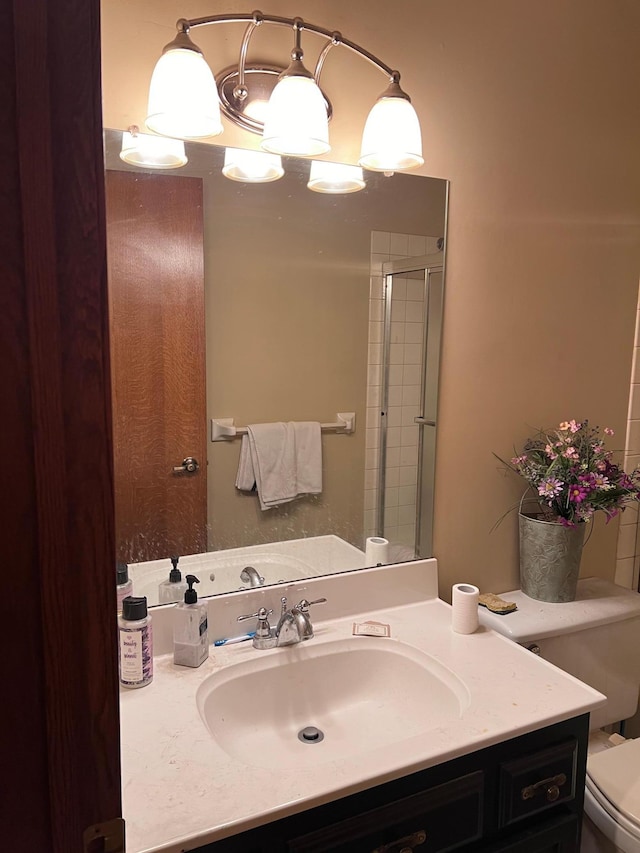 bathroom with toilet, a shower with shower door, vanity, and an inviting chandelier