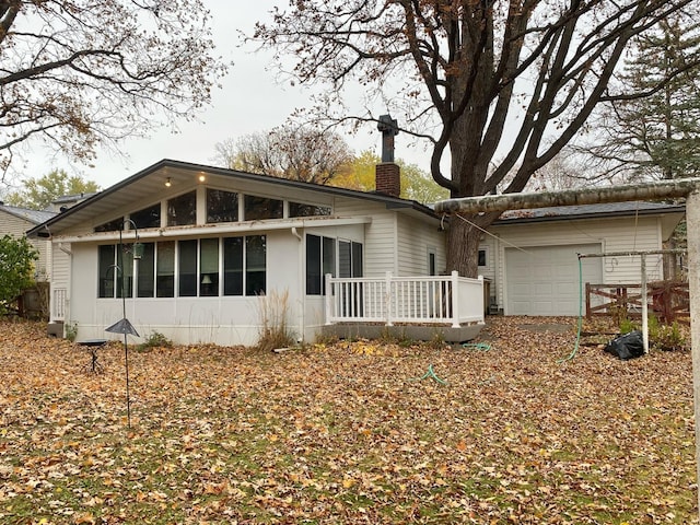 rear view of house featuring a sunroom and a garage