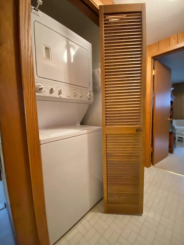 clothes washing area with stacked washer / dryer and a textured ceiling