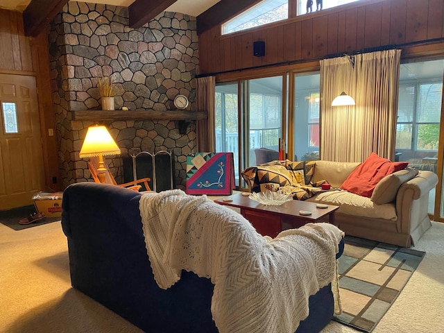 carpeted living room featuring vaulted ceiling with beams, wooden walls, and a fireplace