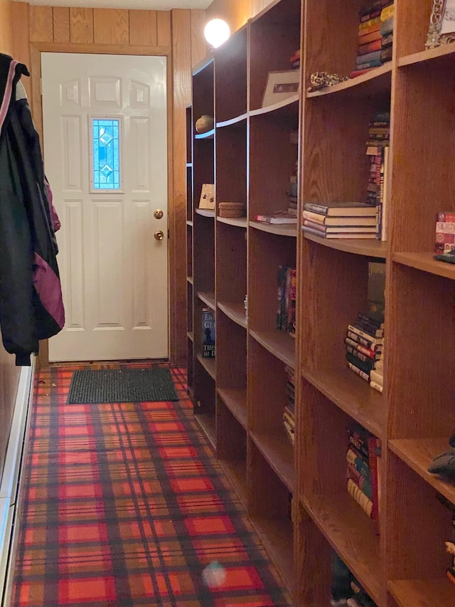 mudroom with wooden walls and dark colored carpet