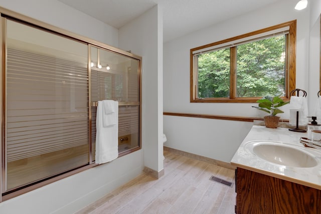 full bathroom with hardwood / wood-style flooring, toilet, vanity, enclosed tub / shower combo, and a textured ceiling