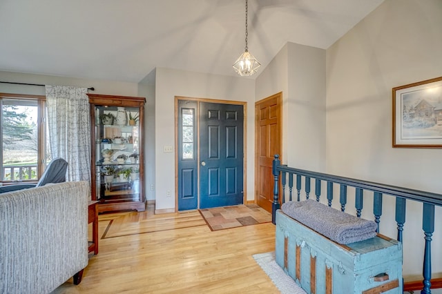 foyer featuring lofted ceiling, hardwood / wood-style flooring, and an inviting chandelier