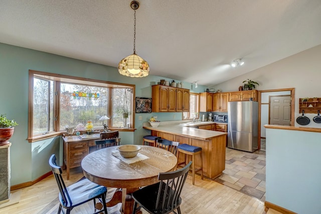 dining area with light hardwood / wood-style floors, lofted ceiling, a textured ceiling, and sink