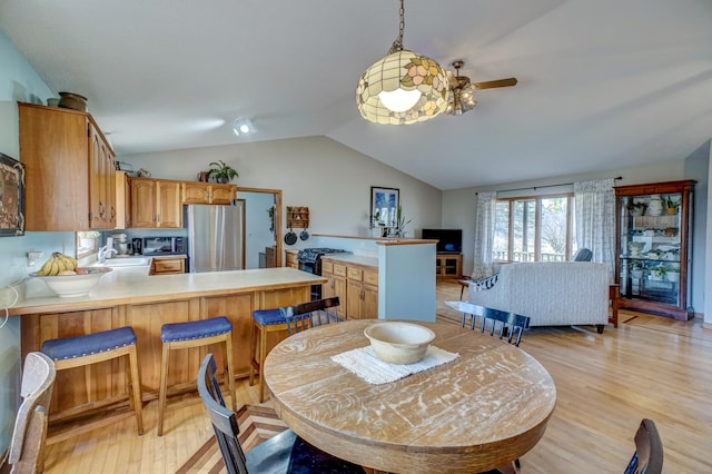 dining area featuring lofted ceiling, sink, light wood-type flooring, and ceiling fan