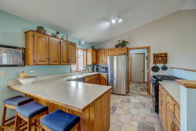 kitchen featuring kitchen peninsula, stainless steel fridge, black gas stove, a kitchen bar, and vaulted ceiling