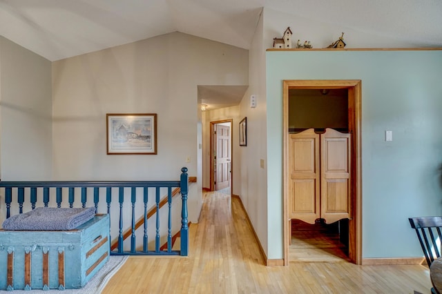 hallway with vaulted ceiling and light wood-type flooring