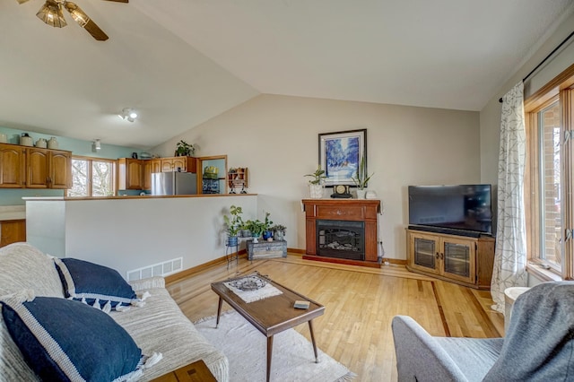 living room featuring light hardwood / wood-style floors, a healthy amount of sunlight, lofted ceiling, and ceiling fan