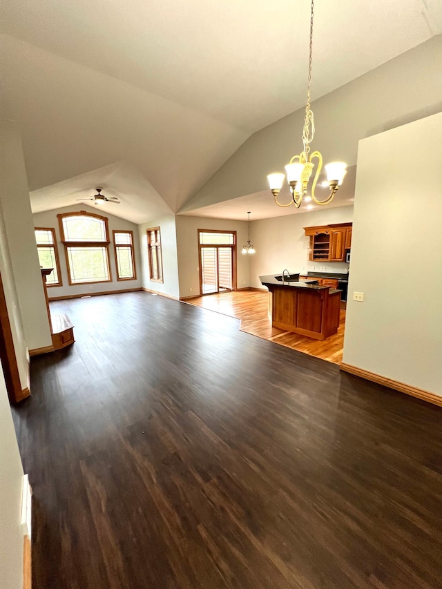 unfurnished living room featuring lofted ceiling, sink, ceiling fan with notable chandelier, and light hardwood / wood-style floors