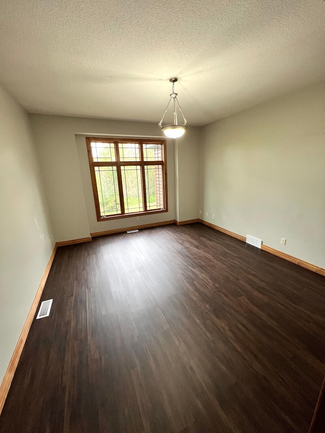 spare room featuring dark wood-type flooring and a textured ceiling