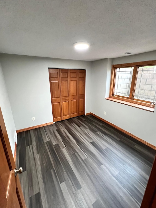 unfurnished bedroom featuring a textured ceiling, a closet, and dark hardwood / wood-style flooring