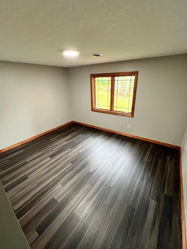 unfurnished room with dark wood-type flooring and a textured ceiling