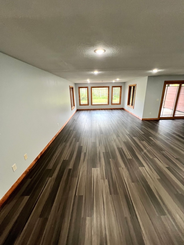 unfurnished room with a textured ceiling and dark hardwood / wood-style floors