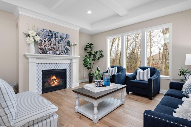 living room with beam ceiling, ornamental molding, light hardwood / wood-style flooring, and a tile fireplace