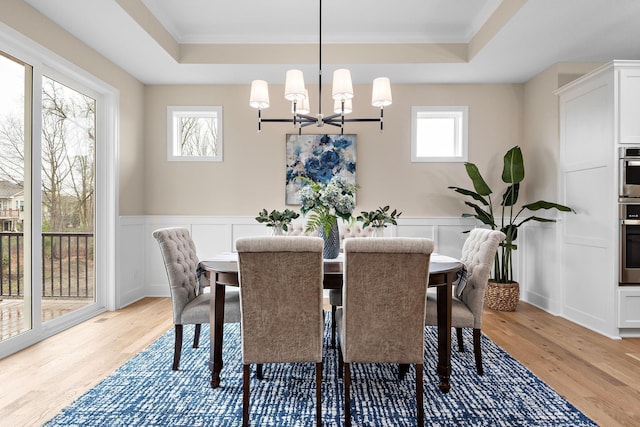 dining space featuring light hardwood / wood-style floors, a tray ceiling, and a wealth of natural light