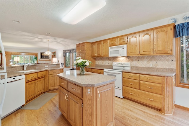 kitchen featuring white appliances, light hardwood / wood-style flooring, decorative light fixtures, and a center island