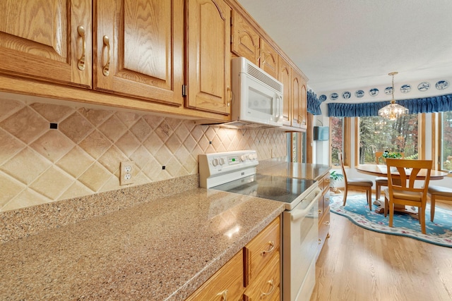 kitchen featuring pendant lighting, white appliances, light hardwood / wood-style flooring, tasteful backsplash, and a notable chandelier