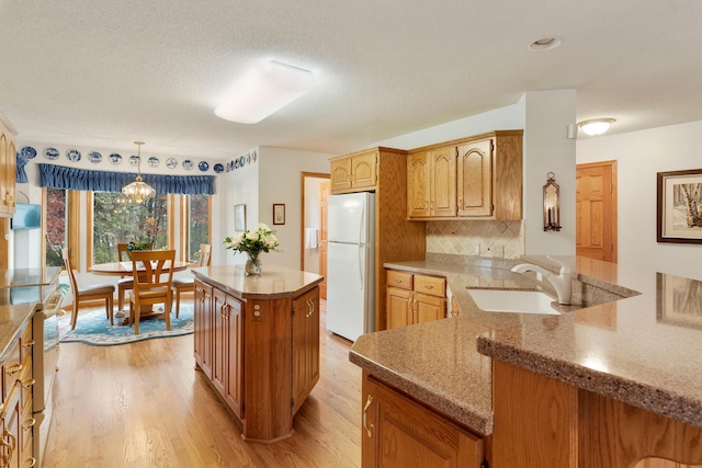 kitchen with pendant lighting, sink, white appliances, light hardwood / wood-style flooring, and tasteful backsplash