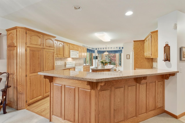 kitchen featuring backsplash, white appliances, a breakfast bar area, and kitchen peninsula