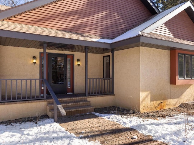 snow covered property entrance featuring a porch