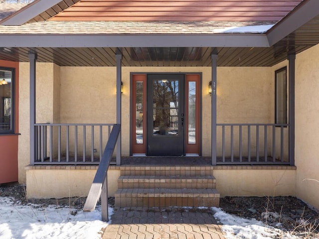 snow covered property entrance featuring a porch