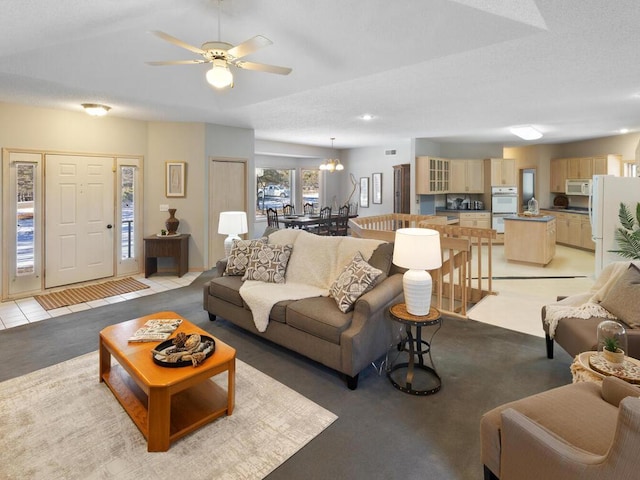 carpeted living room with ceiling fan with notable chandelier