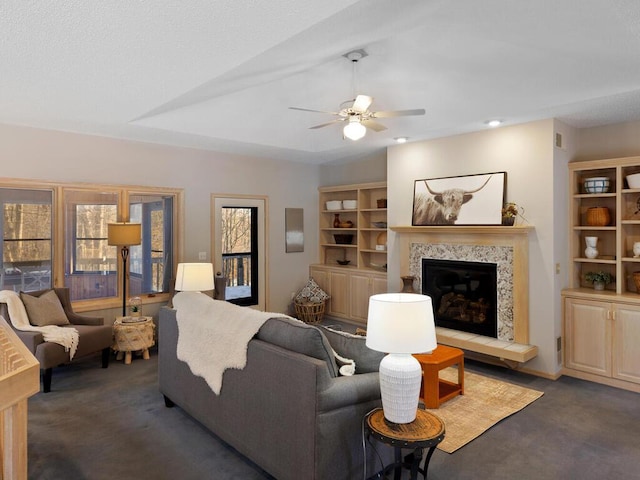 carpeted living room with a tile fireplace and ceiling fan