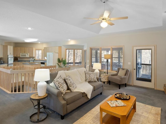 living room featuring ceiling fan, a raised ceiling, dark carpet, and a wealth of natural light