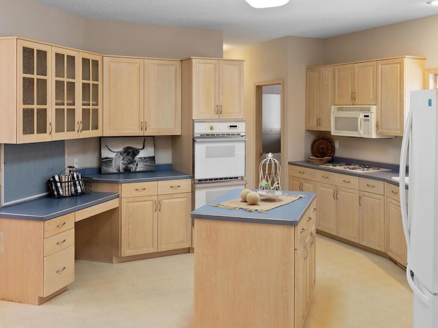 kitchen featuring white appliances, a center island, and light brown cabinets