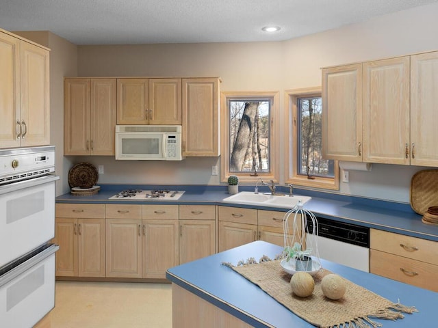 kitchen featuring sink, white appliances, a textured ceiling, and light brown cabinets