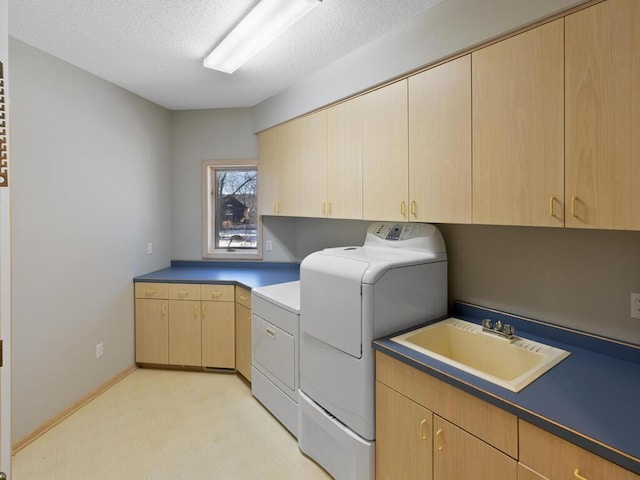 washroom featuring washer and dryer, sink, cabinets, and a textured ceiling