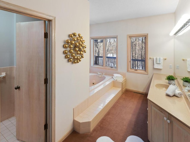 bathroom with tiled tub and vanity