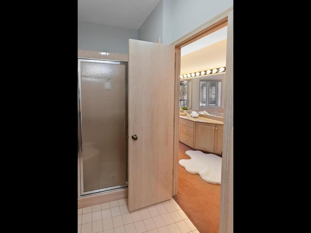 bathroom featuring vanity, a shower with shower door, tile patterned flooring, and a textured ceiling