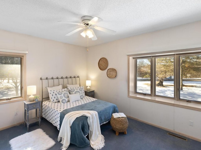 bedroom with ceiling fan, dark carpet, and a textured ceiling