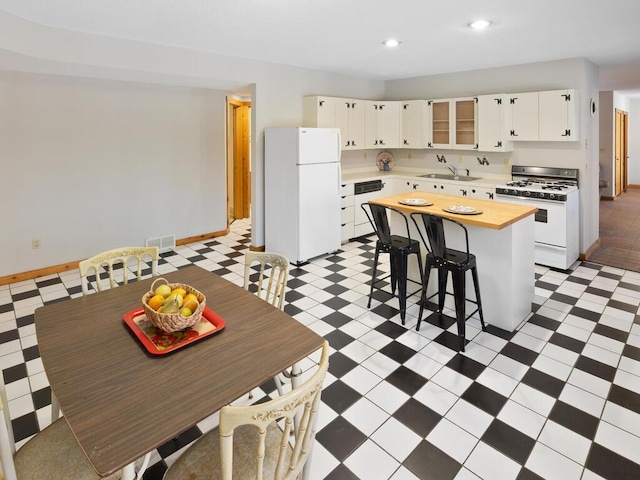 kitchen featuring sink, white appliances, white cabinetry, a kitchen breakfast bar, and a kitchen island