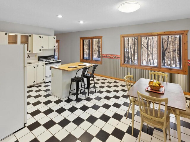 kitchen featuring white appliances, a kitchen breakfast bar, a kitchen island, and white cabinets