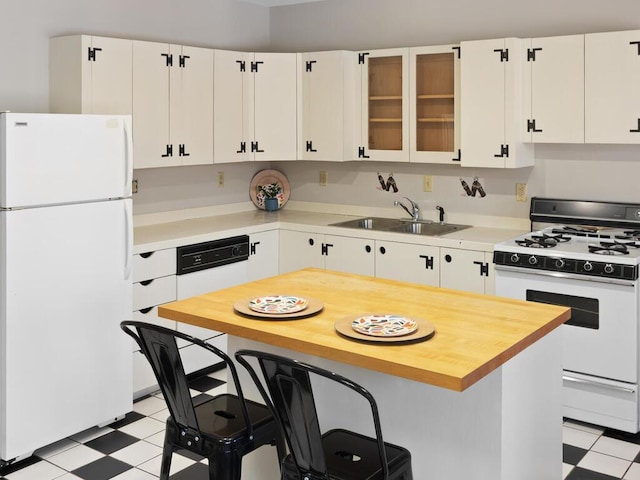 kitchen featuring white appliances, a kitchen bar, sink, and white cabinets