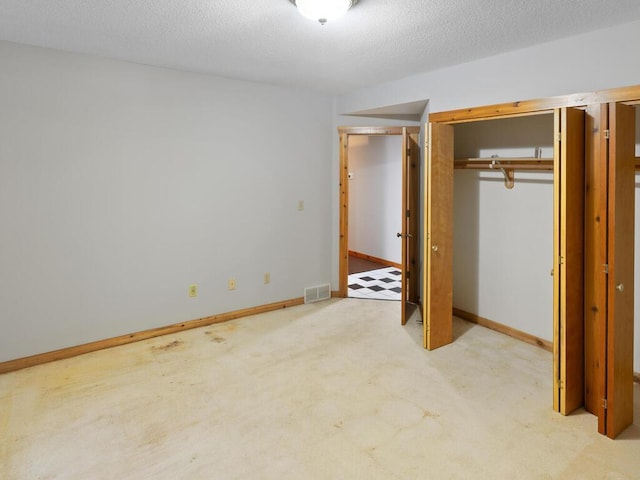 unfurnished bedroom featuring light carpet, a textured ceiling, and a closet