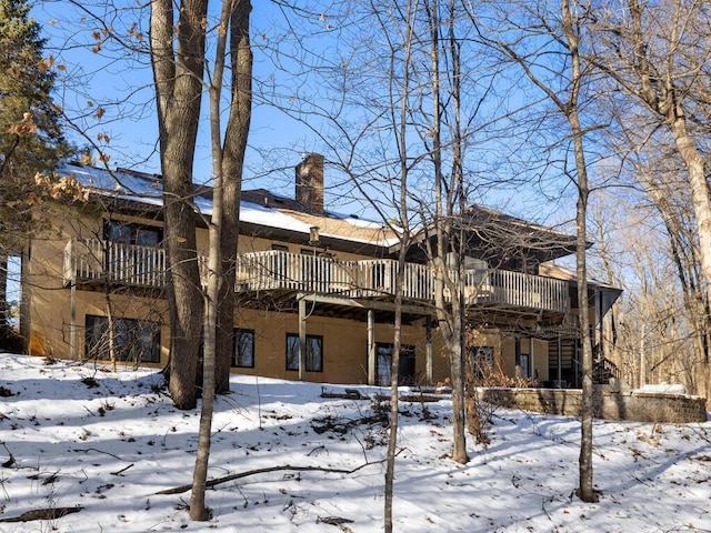 snow covered rear of property featuring a deck