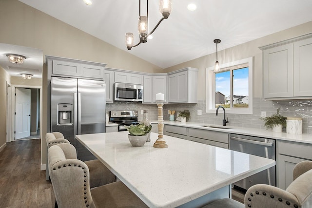 kitchen featuring stainless steel appliances, decorative backsplash, sink, a kitchen island, and decorative light fixtures